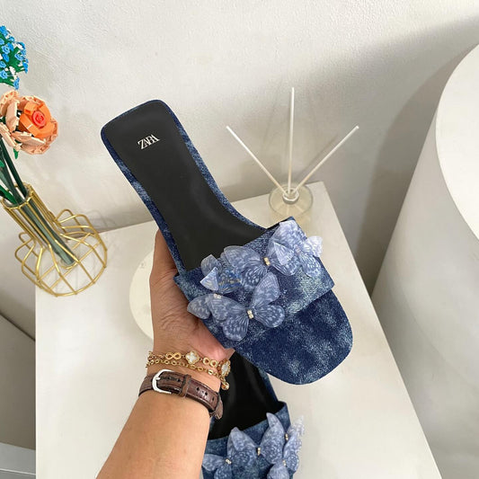 Flat denim sandals. Butterfly shaped embellishment at front