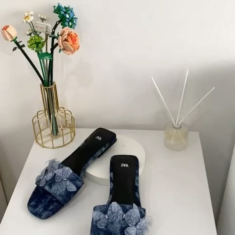 Flat denim sandals. Butterfly shaped embellishment at front